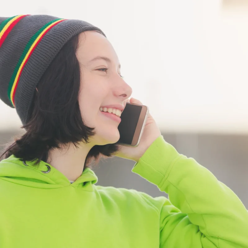 portrait of a beautiful young girl wearing a neon jacket and calling on the phone, dialling an 0435 number on Vodafone