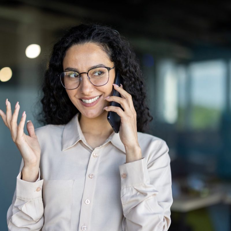 professional woman talking on phone in modern office, calling 0300 number on TalkTalk