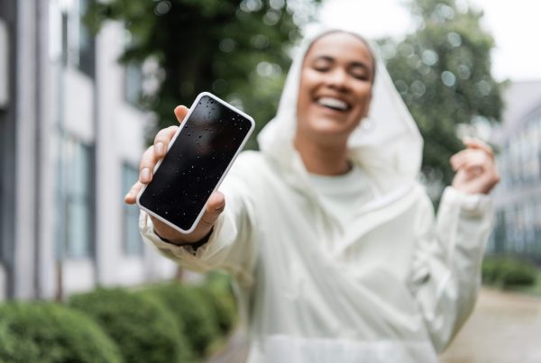 A cheerful woman in white raincoat, holding a mobile phone