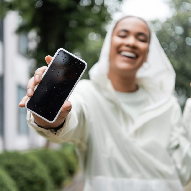 A cheerful woman in white raincoat, holding a mobile phone