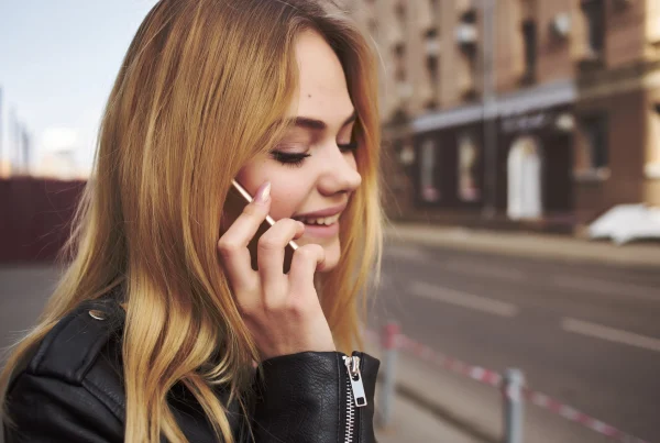 cute blonde in black jacket walking outdoors calling 0300 Number on Virgin Media