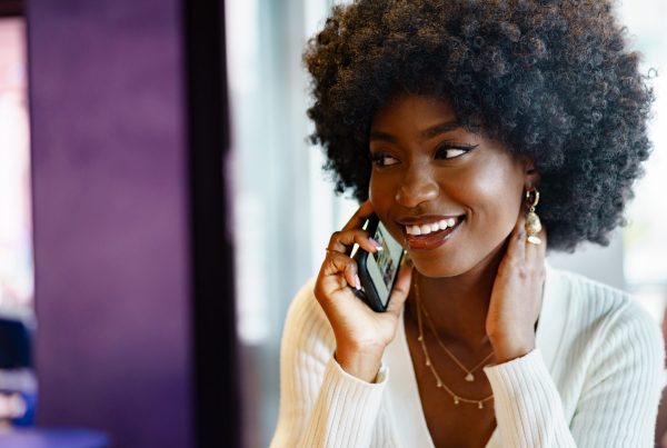smiling young woman talking on cellphone, dialling 0300 number on O2