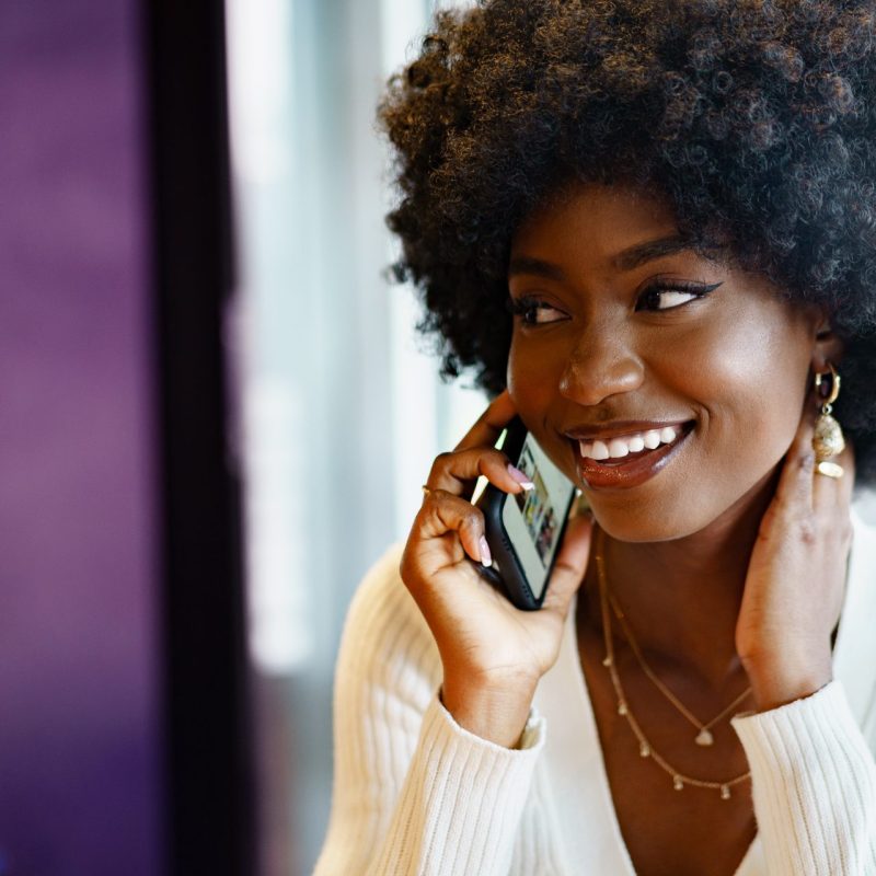 smiling young woman talking on cellphone, dialling 0300 number on O2