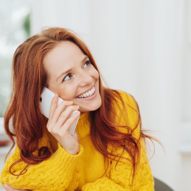 Happy red haired woman talking on a mobile